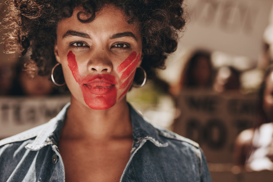 Imagen de una mujer con una huella de mano roja sobre su rostro.